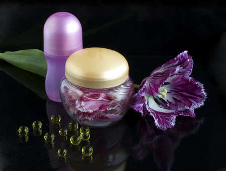 fringed tulip and flower petals in a jar on a black background