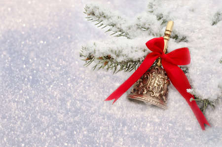 Christmas Red Bell hanging on  snow-covered fir branchの写真素材