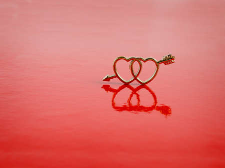 Two gold  hearts are on  red backgroundの写真素材