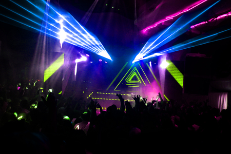 Night club dj party people enjoy of music dancing sound with colorful light with Smoke Machine and lights show. Hands up in the earth.の写真素材