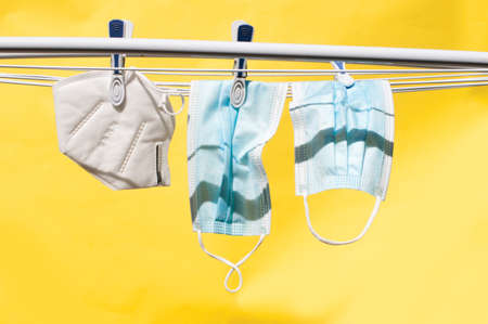 the abstract photo of the  masks fixed with the clothespins drying over the yellow background