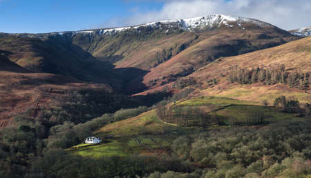 Picture of small white house under Scottish mountains 