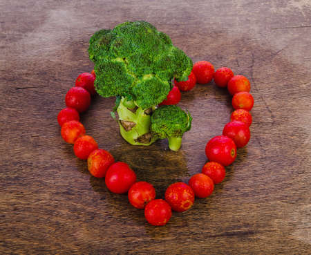 broccoli like a tree standing on a wooden texture, surrounded by red cherry tomatoes in the form of heart, healthy food.の写真素材