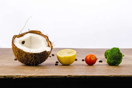 train of coconut, lemon, cherry tomatoes and broccoli on a wooden table on a white background decorated with coffee beansの写真素材
