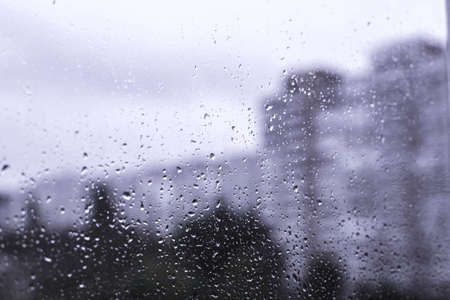 Rain drops on the window in the big city. Big building on the background.の写真素材