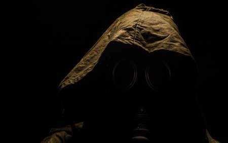 man in the gas mask in the hood, on the black background, survival soldier after apocalypse.の写真素材