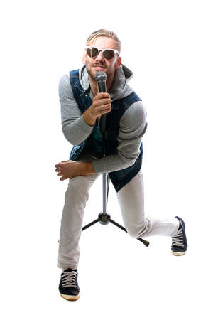 studio portrait of a man singing with microphone isolated on white background, a nice young man with blond hair singing with drive.の写真素材