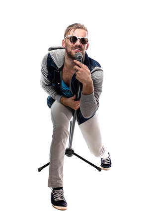 studio portrait of a man singing with microphone isolated on white background, a nice young man with blond hair singing with drive.の写真素材