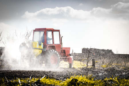 red tractor in a field waters garden, creative backgroundの写真素材