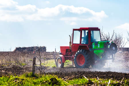 red tractor in a field waters garden, background