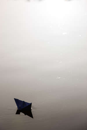 paper boat sailing on water surface at sunsetの写真素材