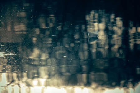 paper boat sailing on water surface at sunsetの写真素材
