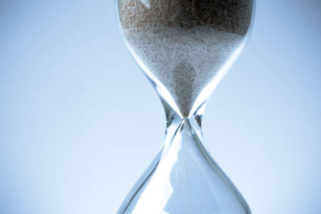 Sand flowing through an hourglass concept for time running out, backgroundの写真素材