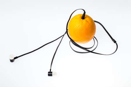 Orange fruit music player: headphones coming from of orange fruit on a white background.の写真素材