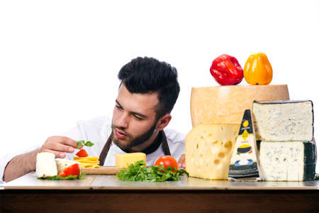 young chef with cheeses enthusiasm builds a composition on a tableの写真素材