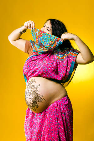 happy pregnant woman in Indian sari, belly and hands painted with hennaの写真素材