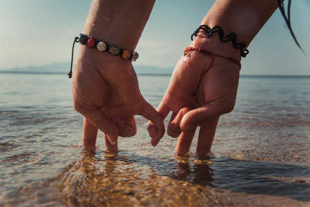 conceptual picture - two hands in the form of couple, walking on the beach at sunrise. personalized hands standing on two fingers symbolizing the people.の写真素材