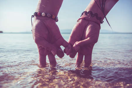 conceptual picture - two hands in the form of couple, walking on the beach at sunrise. personalized hands standing on two fingers symbolizing the people.の写真素材