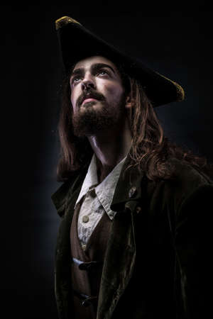 Portrait of a medieval bearded pirate thoughtfully looking up on a black background.の写真素材