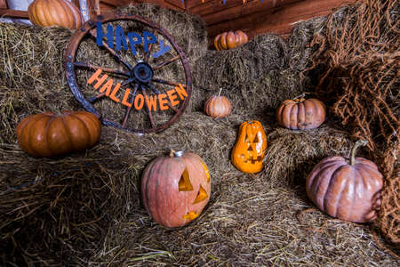 background with happy Halloween inscription and scary jack pumpkins on the hay