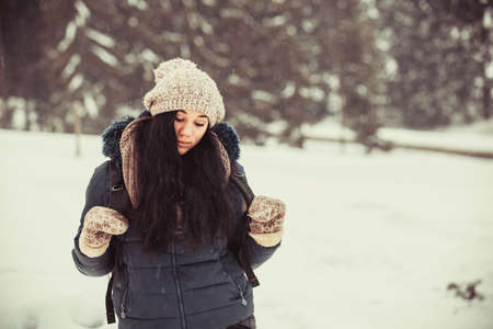 Mysterious, pensive girl in winter against the background of snow and long snow-covered fir trees