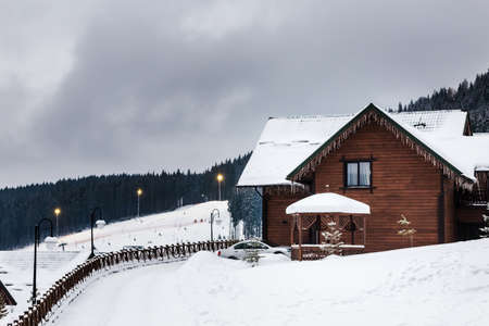 Wooden house in the mountains in winter, a ski track in the background. shallow DOF