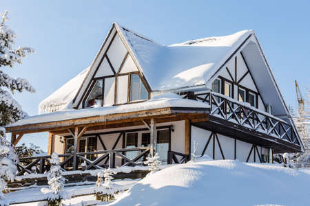 close-up photo of Snow-covered wooden building in the mountains, Construction crane in the...