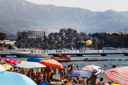 24 august 2017, people are relaxing on the beach on the hive hotel at the background. Water attractions like parasailing,yachting and rapid boat on the sea, Budva, Montenegro.のeditorial素材