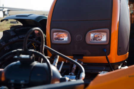 forepart  of new, black and orange tractor, close-up photo