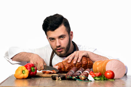 chef isolated on white background, cuts ham and looks into the cameraの写真素材