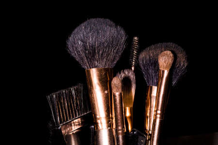 a set of brushes after make-up in a glass, on a black backgroundの写真素材