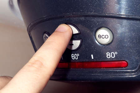 boiler, male finger presses the temperature increase button, close-up photoの写真素材