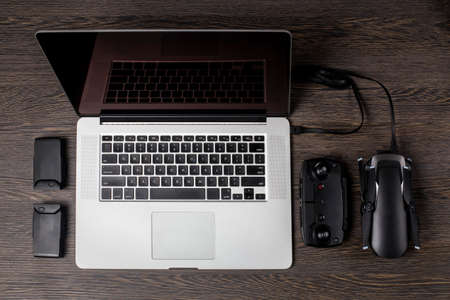 drone connected to laptop near battery on wooden backgroundの写真素材
