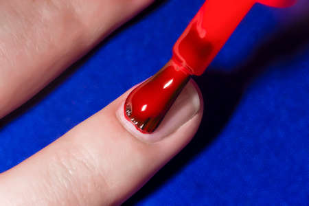 woman paint nails with red lacquer, close-up imageの写真素材