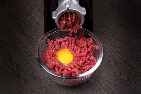 electric meat grinder and a plate of meat on a wooden backgroundの写真素材
