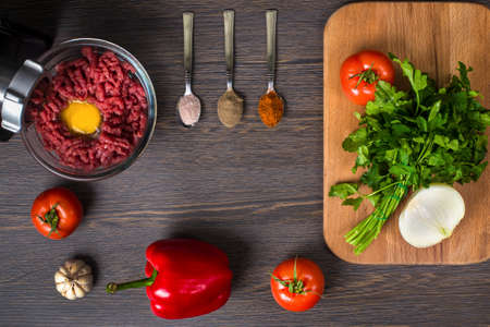 still life of electric meat grinder, tomato, spices, paprika and onion on a wooden background, flat lay image with space for text,の写真素材