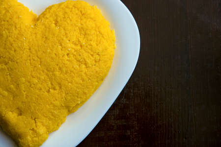 half heart from the ready-made hominy on a white plate on a wooden backgroundの写真素材