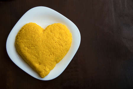 heart from ready hominy on a white plate on a wooden backgroundの写真素材