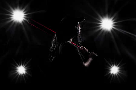 silhouette of a girl with a red bat in the spotlights background imageの写真素材