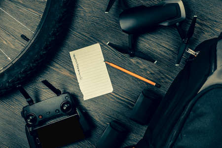 drone and its accessories on a wooden background near a bicycle sheet of paper to write a plan of air filming, toned imageの写真素材