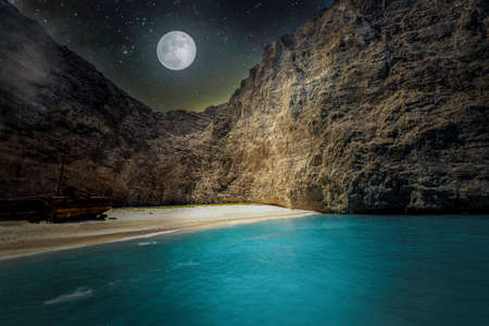 Amazing night landscape of Navagio beach with shipwreck on Zakynthos island, starry sky and a full moon on the background, Greece.の写真素材