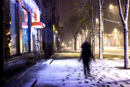 Blurred or defocused image of girl walking through the snowy street of the night cityのeditorial素材