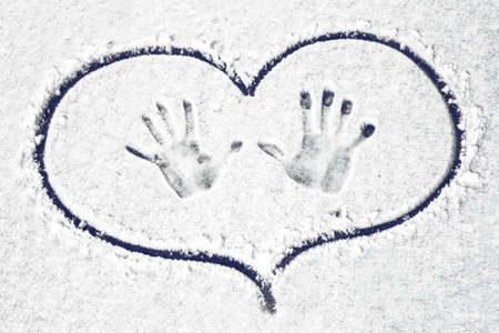 Handprints on the snow circled in heart, background imageの写真素材