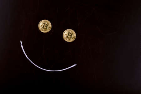 face on a black background, eyes from bitcoins and a smile in chalk, an image with space for textの写真素材