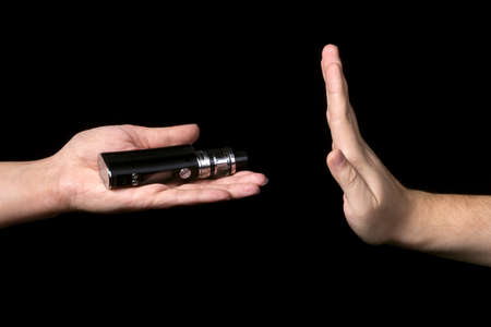 female hand holding an electronic cigarette offering a man but he refuses, on black background