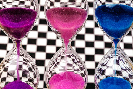 colorful hourglass on the background of the chess wallの写真素材