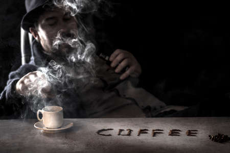 the inscription coffee on the table, a man in blur smokes an electronic cigarette on the backgroundの写真素材