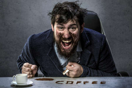 a bearded man smeared with coffee, emotionally shouts looking into the camera, the concept of coffee is a drugの写真素材