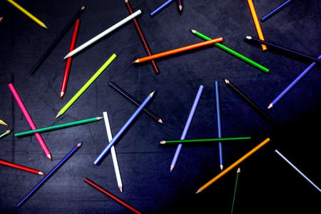 colored pencils for drawing arranged in a chaotic manner on a black background