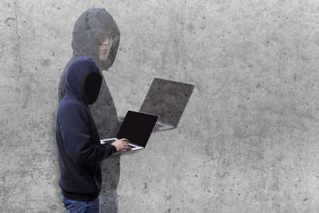 two-faced hacker hood and shadow with a face on a concrete background